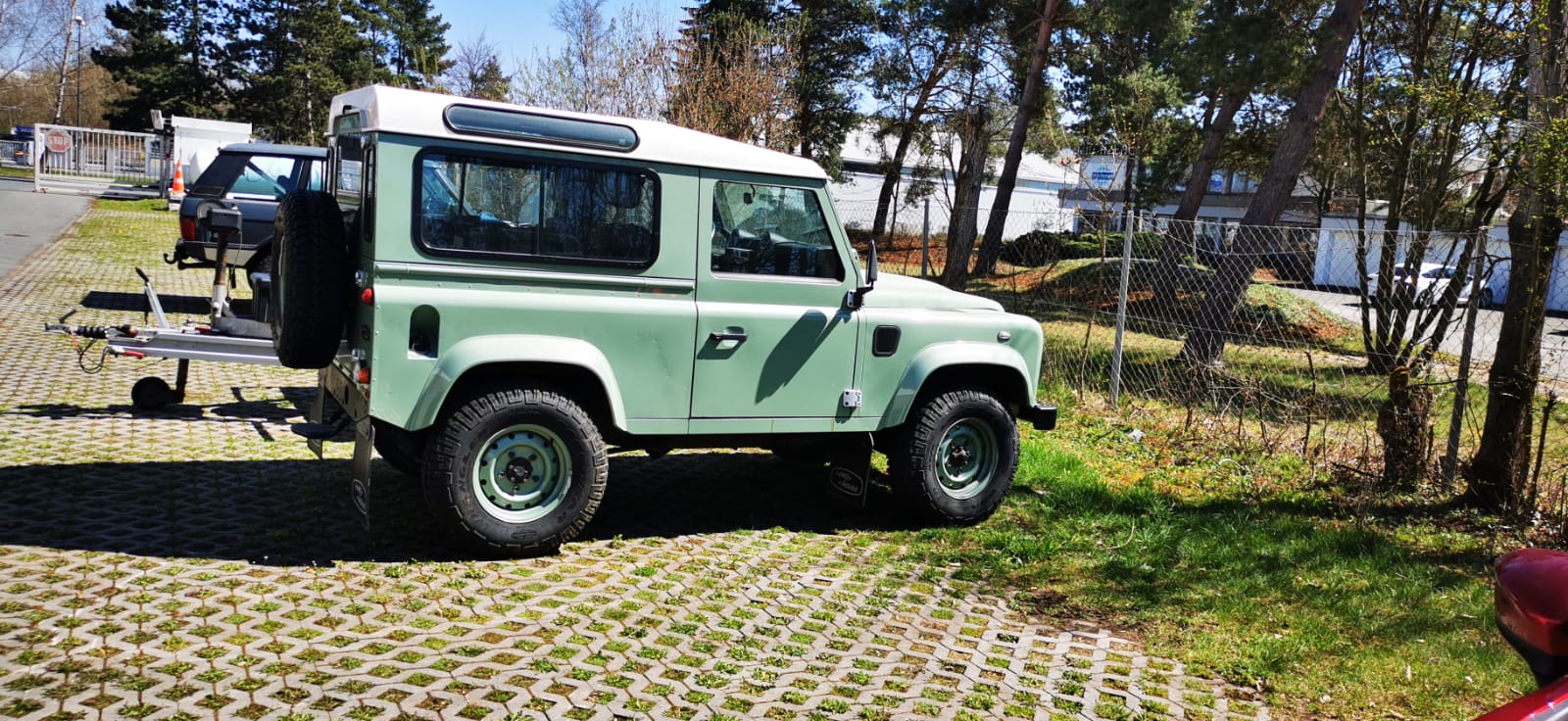 Grüner Rover mit weißem Dach auf dem Parkplatz vor der Werkstatt