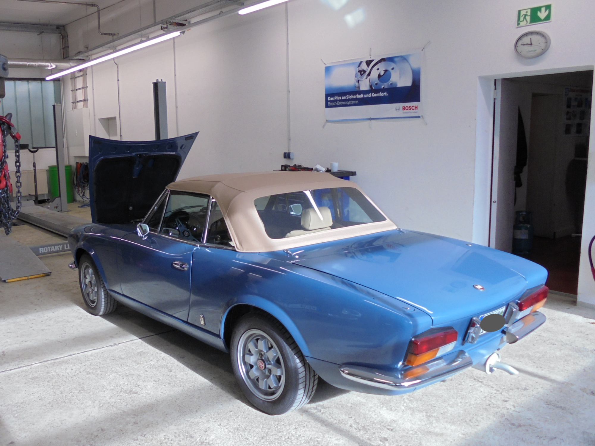 blauer FIAT 124 Spider mit offener Motorhaube steht zur Prüfung in der Weidener Werkstatt bereit