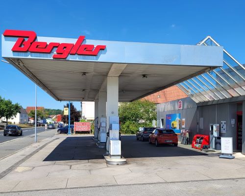 Tankstelle mit der roten Aufschrift Bergler am Tankstellendach. Rechterhand der Eingang zum Shop.