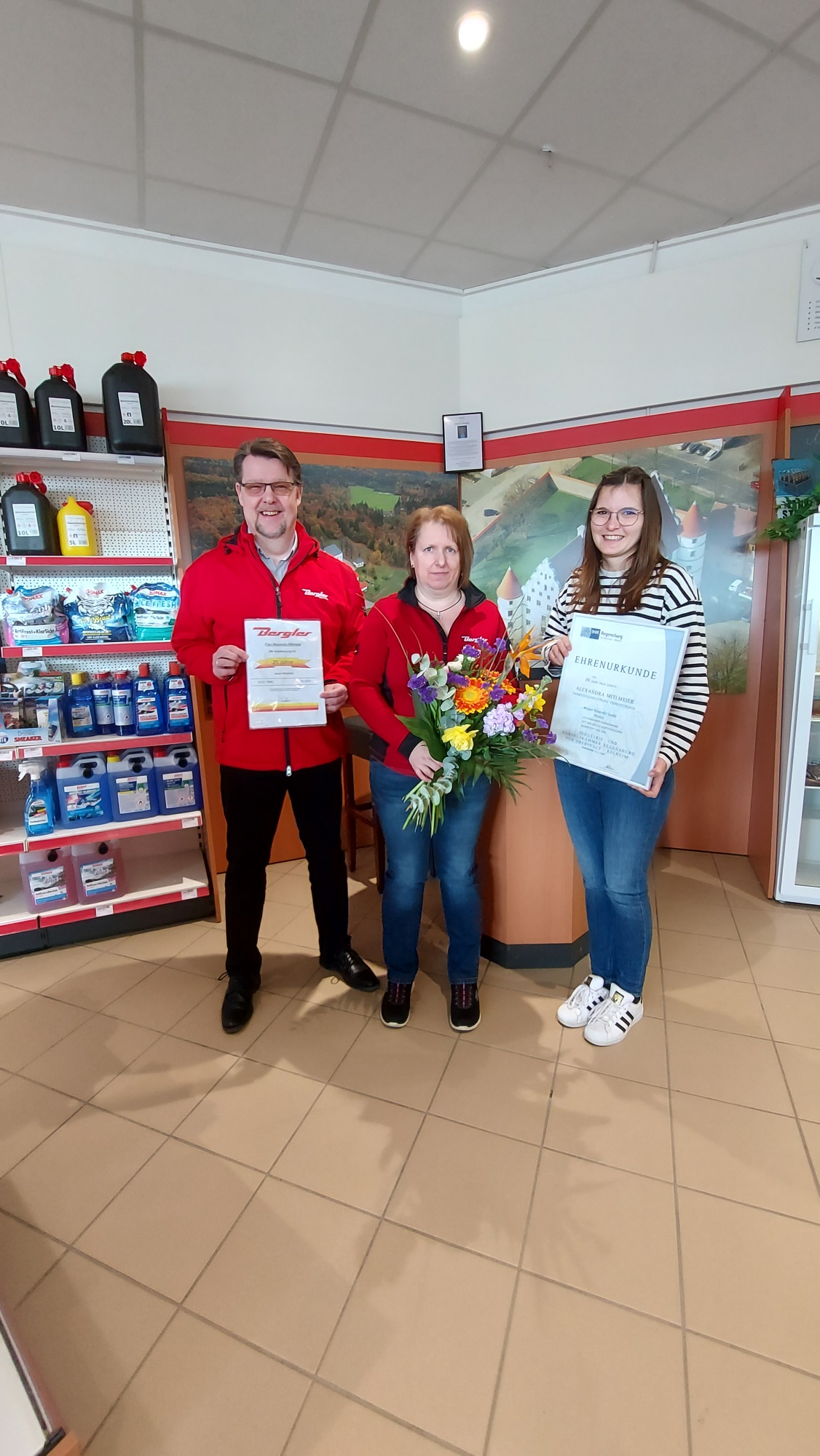 Auf dem Bild sieht man Frau Mitlmeier (Leitung Tankstelle), die zusammen mit Herrn Schneider (Betriebsleiter) und Frau Bösl (Assistenz Geschäftsführer), das 25-Jährige Betriebsjubiläum feiert.
