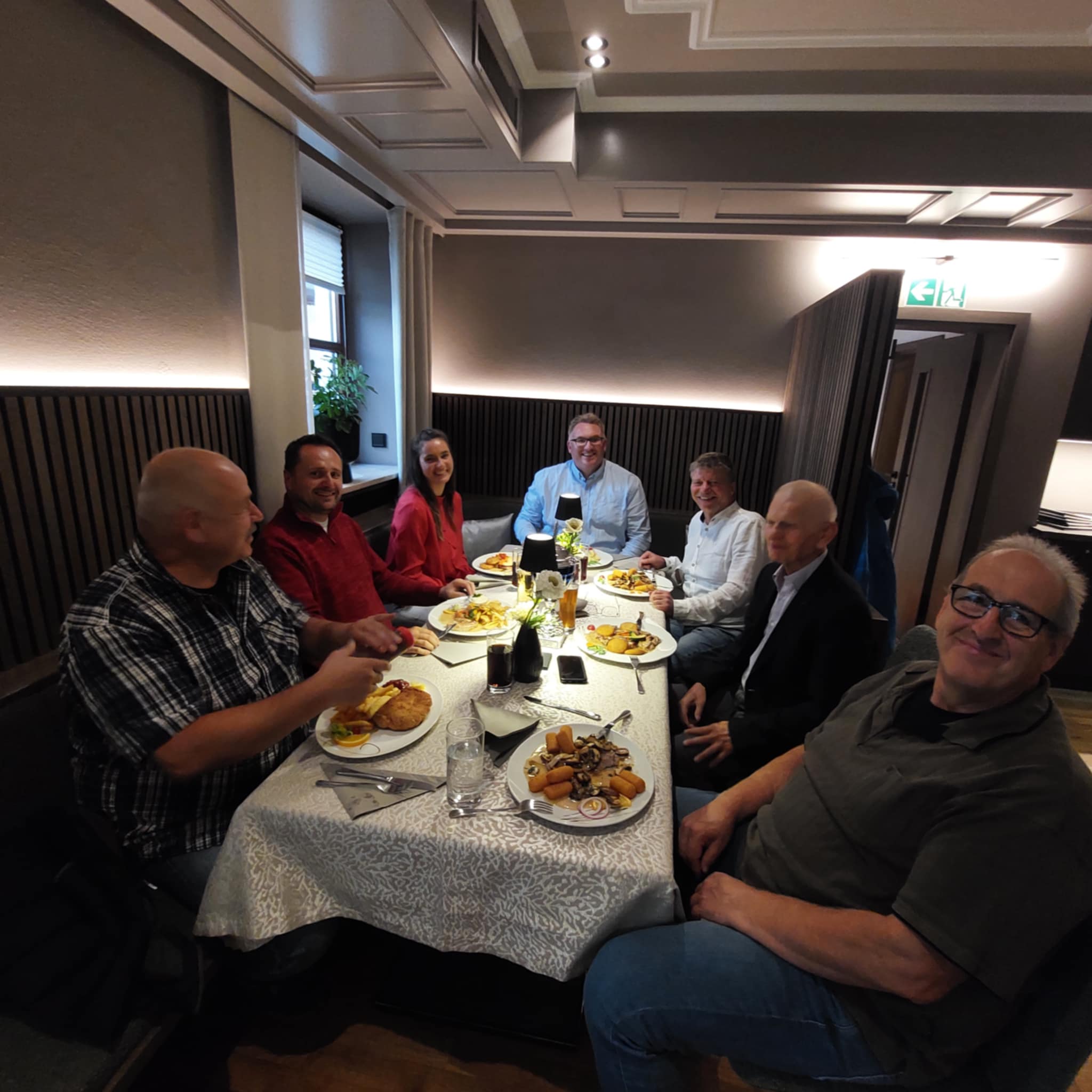 Gruppe von sieben Kollegen beim gemeinsamen Abendessen im Restaurant