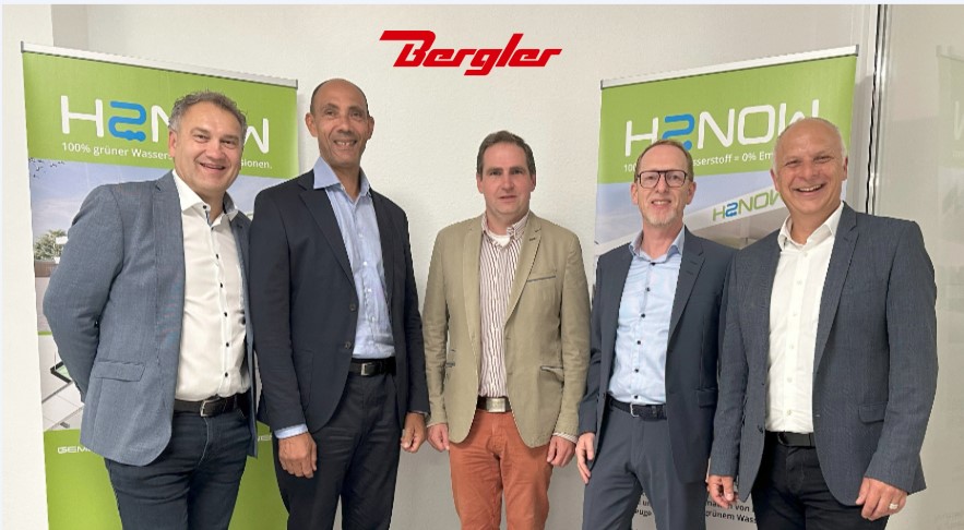Im Vordergrund die 5 beteiligten Herren mit Sakko, im Hintergrund Roll-Ups von H2Now